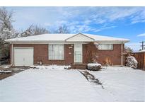 Brick ranch home with snow-covered yard and attached garage at 205 E 106Th Pl, Northglenn, CO 80233