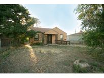 A beige ranch house with a front yard and mature trees at 7261 Magnolia St, Commerce City, CO 80022