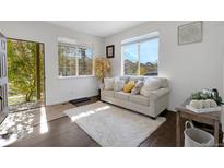 Cozy living room with hardwood floors, a light-colored couch, and natural light at 14449 E 101St Pl, Commerce City, CO 80022