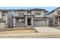 Two-story home with gray siding, stone accents, and two-car garage at 3045 S Poppy St, Morrison, CO 80465