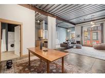 Open concept living area with exposed beams and large windows at 910 Santa Fe Dr # 19, Denver, CO 80204