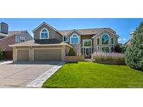 Two-story home with brick facade, three-car garage, and landscaped lawn at 8935 Green Meadows Ct, Highlands Ranch, CO 80126