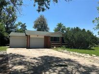 Brick ranch home with attached two-car garage and a partially fenced yard at 12154 E Virginia Dr, Aurora, CO 80012