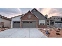 Two-story house with gray siding, stone accents, and a two-car garage at 3856 Treadway Pt, Castle Rock, CO 80108