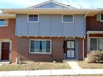 Brick and gray two-story townhome with a security door and landscaping at 1165 Milky Way, Thornton, CO 80260