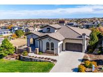 Luxury home with stucco exterior, tile roof, and a three-car garage, offering stunning views at 7912 Galileo Way, Littleton, CO 80125