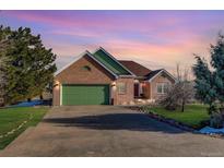 Brick ranch home with green accents, attached garage, and a large driveway at 4270 Defoe St, Strasburg, CO 80136