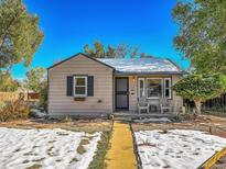 Tan house with dark shutters, small front porch, and snowy yard at 1794 Verbena St, Denver, CO 80220