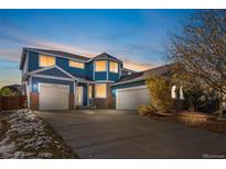Two-story house with a blue exterior, brick accents, and a three-car garage at 12956 E 107Th Pl, Commerce City, CO 80022
