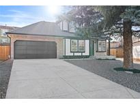 Charming two-story home with a gray driveway and landscaped yard at 13750 W 65Th Ave, Arvada, CO 80004