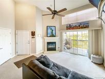 Bright living room with fireplace, vaulted ceiling, and access to balcony at 9481 E Mansfield Ave # 305, Aurora, CO 80014