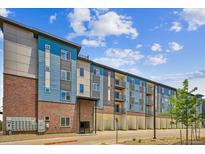 Modern apartment building with brick and blue siding, featuring multiple levels and parking at 487 Interlocken Blvd # 303, Broomfield, CO 80021