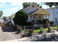 Charming one-story home with a yellow front porch and roses at 284 N 8Th Ave, Brighton, CO 80601