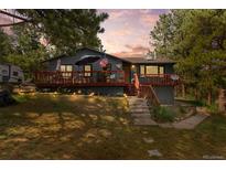 Ranch-style home with deck, landscaping, and mountain views at 7146 Julie Ln, Evergreen, CO 80439