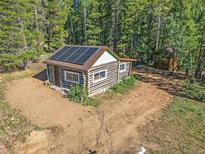 Aerial view of a rustic log cabin with solar panels at 9719 Beaver Pond, Conifer, CO 80433