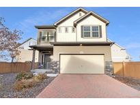 Two-story house with a light brown exterior, a two-car garage, and a landscaped front yard at 10105 Zeno St, Commerce City, CO 80022