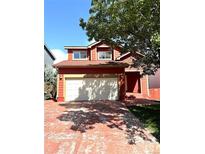 Two-story red house with a two-car garage and well-manicured lawn at 7958 Downing St, Denver, CO 80229