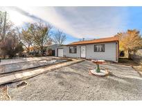 Cute bungalow with a gravel front yard, walkway, and mature trees at 7651 Kearney Dr, Commerce City, CO 80022