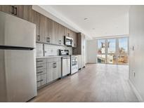 Modern kitchen with stainless steel appliances and wood cabinets at 3575 Chestnut Pl # 601, Denver, CO 80216