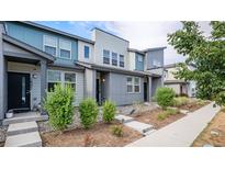 Modern townhome exterior with gray and teal siding, landscaping, and walkway at 16231 E Warner Pl, Denver, CO 80239