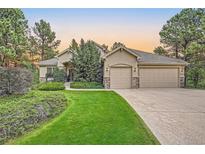 Two-story house with three-car garage and manicured lawn at 7454 Cameron Dr, Larkspur, CO 80118