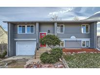 Gray two-story house with a red door, attached garage, and landscaped yard at 486 Leona Dr, Denver, CO 80221