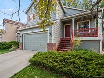 Two-story home with attached garage and red front door at 9629 Queenscliffe Dr, Highlands Ranch, CO 80130