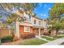 Tan and brick townhouse exterior with landscaping and a paved walkway at 1199 S Waco St # E, Aurora, CO 80017
