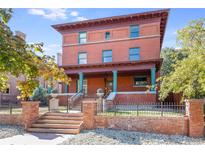 Brick two-story home with a classic design, inviting porch, and landscaped yard at 965 N Pennsylvania St, Denver, CO 80203