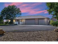 House exterior at dusk with three car garage and landscaped yard at 11685 Salem St, Henderson, CO 80640