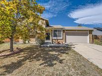 House exterior featuring a tan brick facade, attached garage, and landscaping at 7679 S Independence Way, Littleton, CO 80128