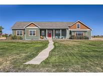 Ranch style home with green siding and red door at 738 S Main St, Byers, CO 80103