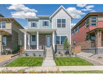 Two-story home with light blue and gray siding, brick accents, and a front porch at 21278 E 63Rd Dr, Aurora, CO 80019