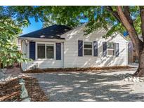 Charming white house with blue shutters, gravel driveway, and mature trees at 1160 S Monroe St, Denver, CO 80210