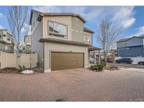 Two-story townhome with brown garage door and brick paver driveway at 18561 E 53Rd Ave, Denver, CO 80249