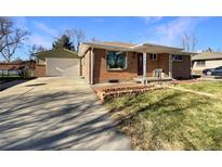 Brick ranch home with attached garage and landscaped front yard at 6045 Garrison St, Arvada, CO 80004