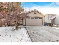 Tan house exterior with a two-car garage and snow-covered front yard at 11532 E 1St Ave, Aurora, CO 80010