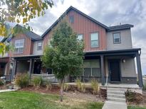 Two-story townhome with gray and brown siding, front porch, and landscaped yard at 11137 E 25Th Ave, Aurora, CO 80010