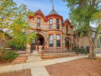 Two-story home with stone exterior, arched entryways, and a charming front porch at 3611-3615 Osage St, Denver, CO 80211
