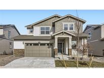 Two-story house with gray and white siding, a two-car garage, and landscaping at 4823 Astor Pl, Brighton, CO 80601