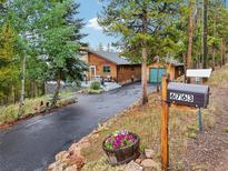 Exterior of a charming log home with a spacious deck and mountain views at 6763 Deer Path, Evergreen, CO 80439