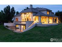 Luxury home with a large deck, stonework, and landscaping at dusk at 160 Ponderosa Dr, Boulder, CO 80303