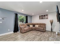Living room featuring a large sectional sofa, wood-look floors, and accent wall at 3726 E 112Th Pl, Thornton, CO 80233