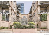 Exterior of a light beige three-story building with balconies and lush landscaping at 1200 Cherokee St # 206, Denver, CO 80204