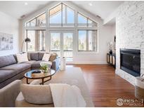 Spacious living room with hardwood floors, large windows, and a cozy fireplace at 385 Baxter Farm Ln, Erie, CO 80516