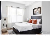 Bright bedroom with a king-size bed, modern dark wood platform bed frame, and orange throw pillows at 1707 Walnut St # 203, Boulder, CO 80302