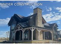 Under construction, two-story home with stone and wood exterior, solar panels, and covered porch at 917 Latigo Loop, Lafayette, CO 80026