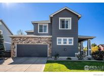 Two-story house with gray siding, stone accents, and a two-car garage at 5558 Longs Peak St, Brighton, CO 80601