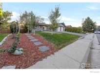 Ranch-style home with landscaped yard and stone pathway at 3955 S Uinta St, Denver, CO 80237