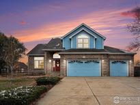 Two-story house with a blue exterior, double garage, and landscaping at 18715 Wagon Trl, Mead, CO 80542